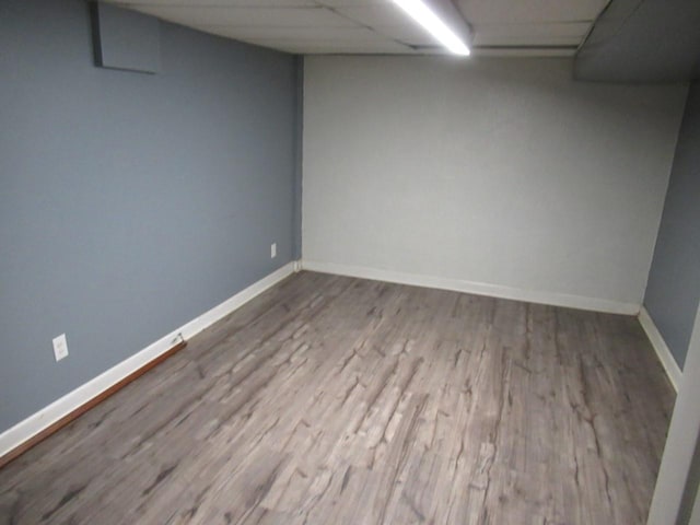 finished basement with baseboards, a drop ceiling, and wood finished floors