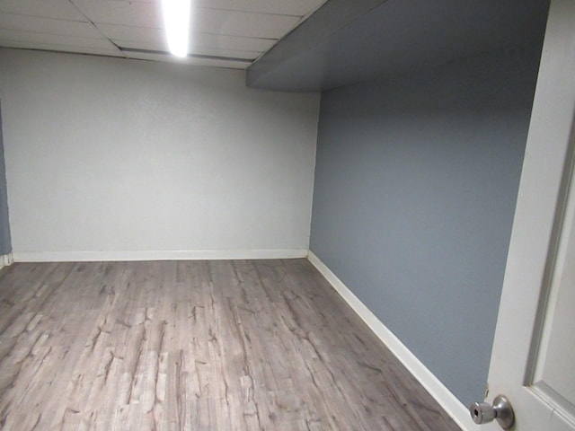 unfurnished room with a drop ceiling, baseboards, and wood finished floors