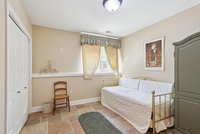 bedroom featuring stone finish floor, visible vents, baseboards, and a closet