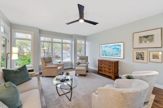 living room featuring ceiling fan, baseboards, and wood finished floors