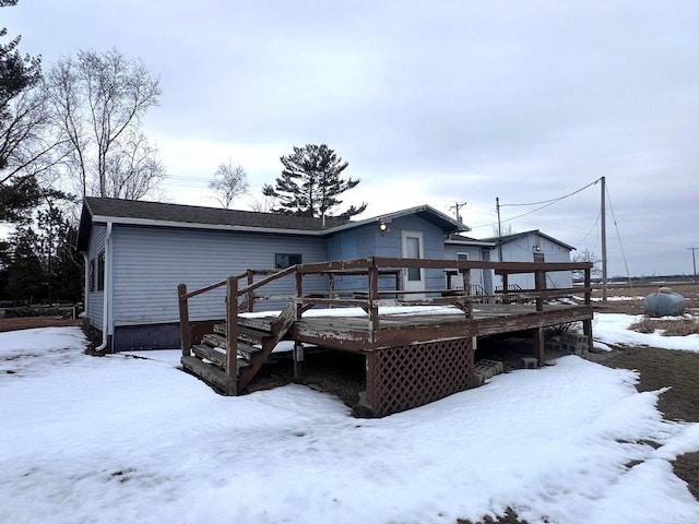 snow covered back of property featuring a wooden deck