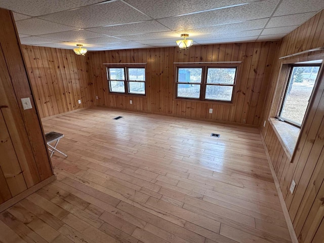 unfurnished room with light wood-style floors, visible vents, and a wealth of natural light