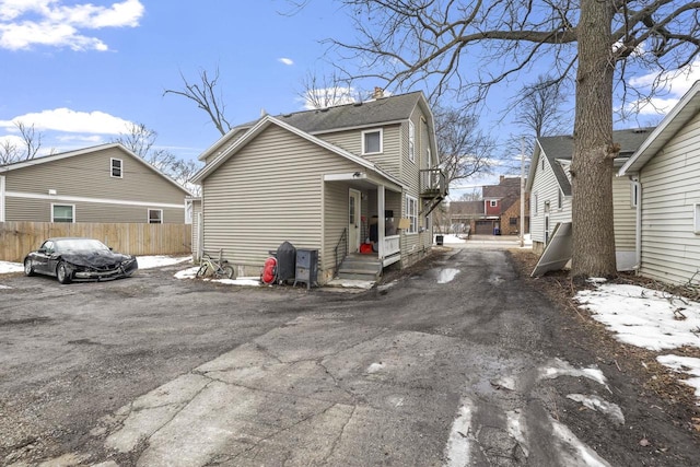 view of property exterior with driveway, a chimney, and fence