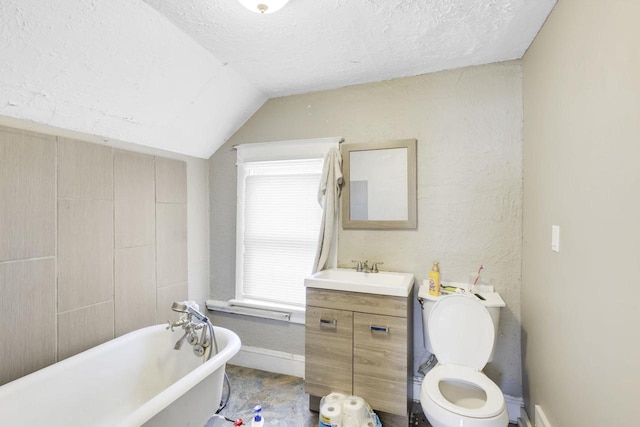 full bathroom featuring a textured ceiling, vanity, baseboards, vaulted ceiling, and a freestanding bath