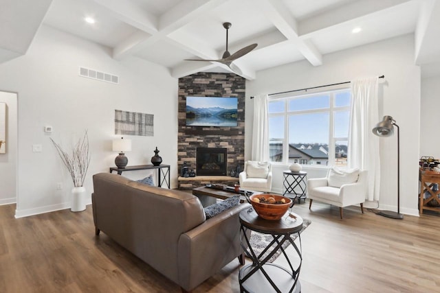 living room with visible vents, a stone fireplace, baseboards, and wood finished floors