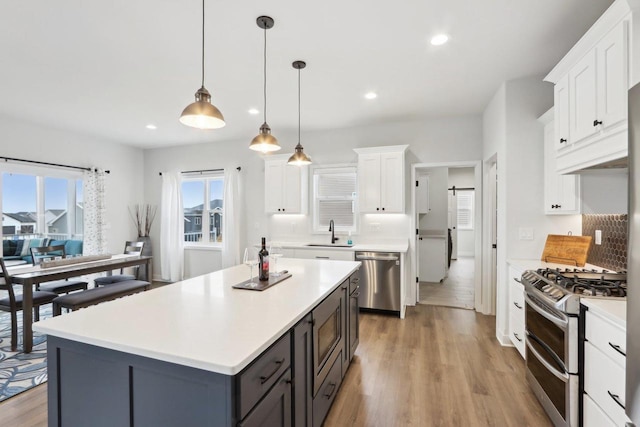 kitchen with stainless steel appliances, a sink, light countertops, and white cabinets