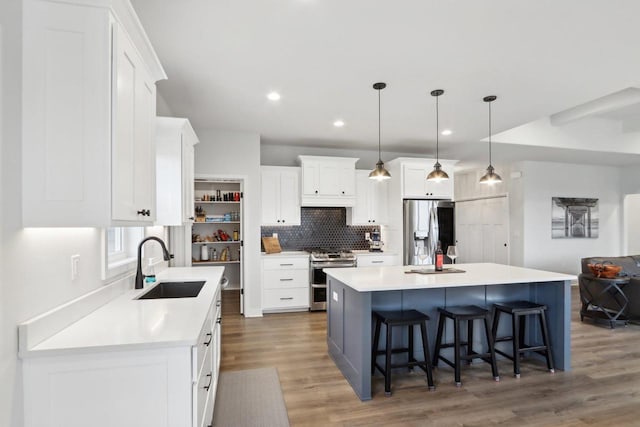 kitchen with tasteful backsplash, a breakfast bar, stainless steel appliances, white cabinetry, and a sink