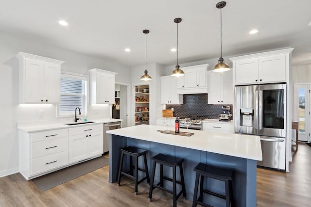 kitchen with a breakfast bar, appliances with stainless steel finishes, dark wood-type flooring, white cabinetry, and a sink