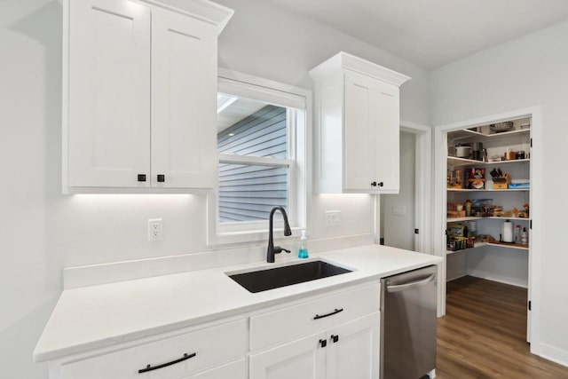 kitchen featuring light countertops, stainless steel dishwasher, a sink, and white cabinets