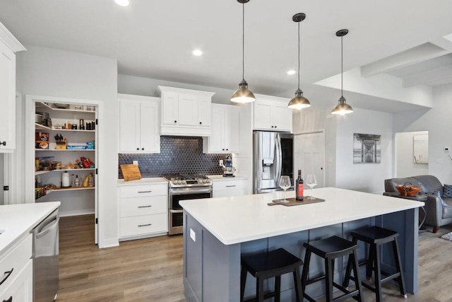 kitchen featuring appliances with stainless steel finishes, light wood-style floors, decorative backsplash, and a kitchen island