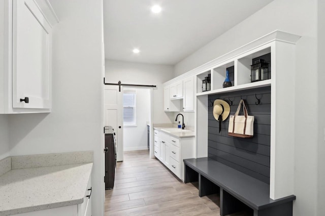 mudroom featuring light wood-type flooring, a barn door, a sink, and recessed lighting