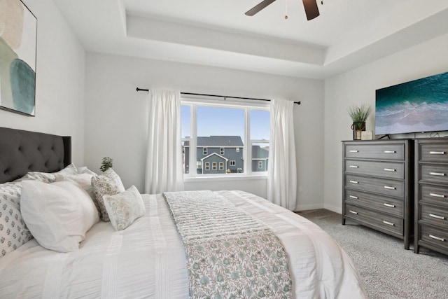 bedroom with carpet, a raised ceiling, a ceiling fan, and baseboards