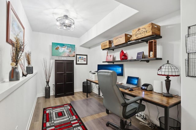 home office with baseboards, a chandelier, and wood finished floors