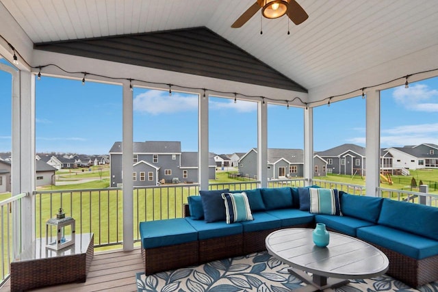 sunroom / solarium with a residential view, vaulted ceiling, and a ceiling fan