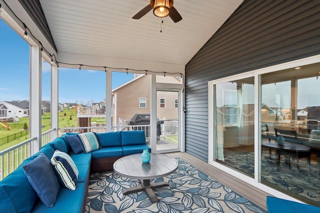 sunroom featuring vaulted ceiling, ceiling fan, and a residential view