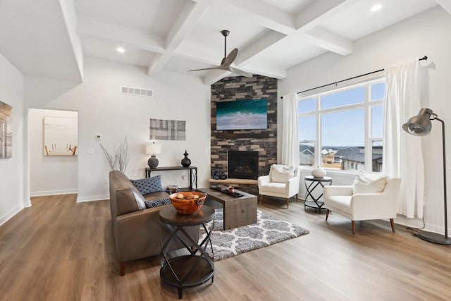 living area featuring a ceiling fan, visible vents, baseboards, and wood finished floors