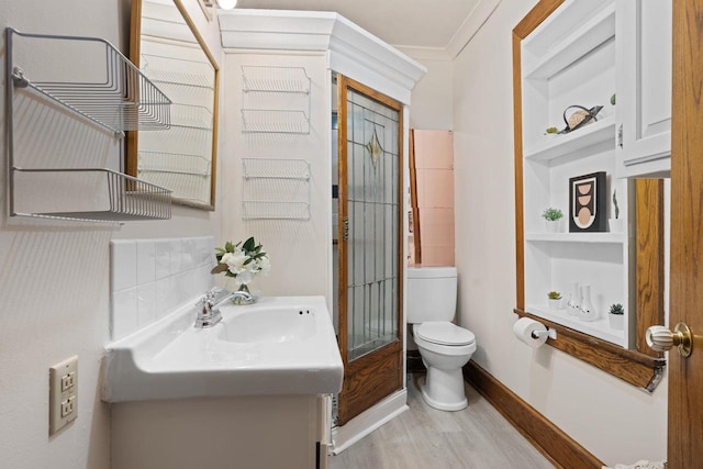 bathroom featuring built in shelves, crown molding, toilet, vanity, and wood finished floors