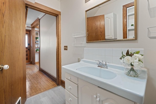 bathroom featuring visible vents, decorative backsplash, vanity, wood finished floors, and baseboards