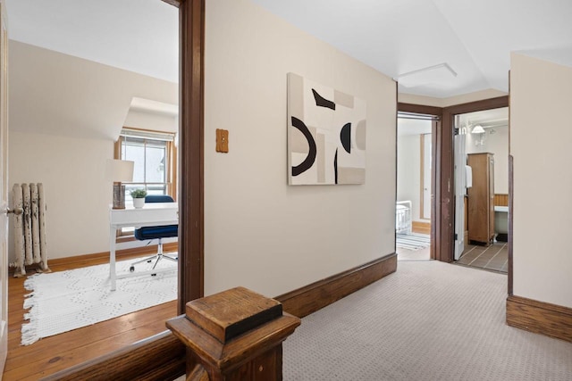 hallway with lofted ceiling, light carpet, and baseboards