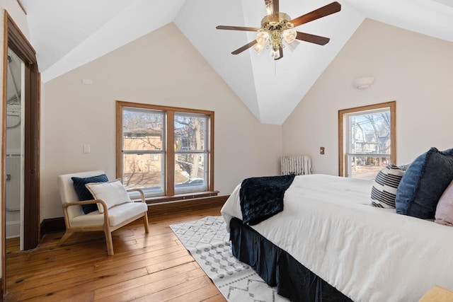 bedroom featuring high vaulted ceiling, hardwood / wood-style floors, multiple windows, and a ceiling fan