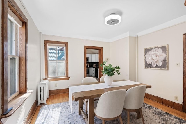 dining area with baseboards, light wood finished floors, and radiator heating unit