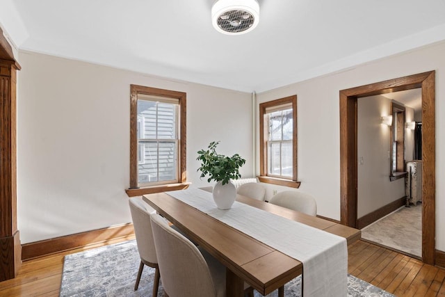 dining space featuring light wood-style flooring, visible vents, radiator heating unit, and baseboards