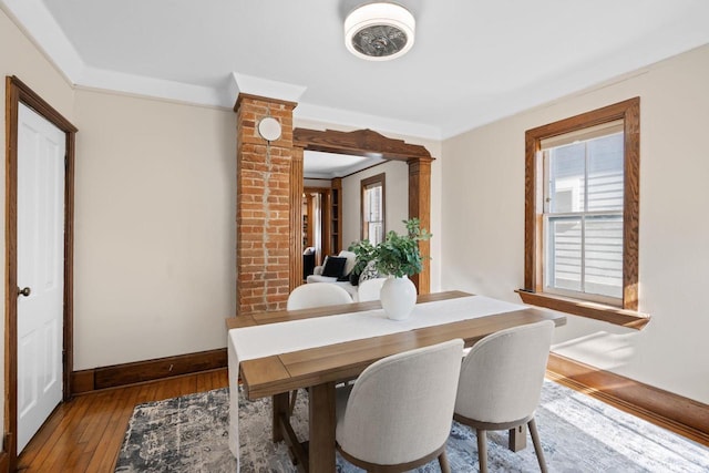 dining room with ornamental molding, wood-type flooring, decorative columns, and baseboards