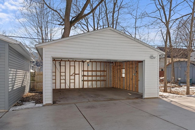 snow covered garage featuring a garage and fence