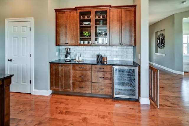 bar featuring baseboards, wine cooler, wood finished floors, and decorative backsplash