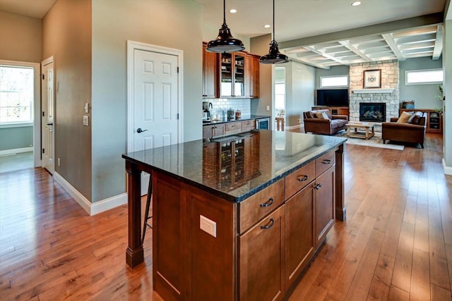 kitchen featuring pendant lighting, brown cabinetry, glass insert cabinets, a kitchen island, and a kitchen bar