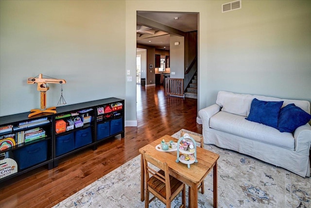 living room featuring dark wood-style floors, visible vents, baseboards, and stairs