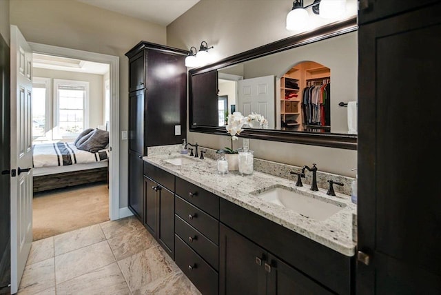 ensuite bathroom with double vanity, ensuite bath, a spacious closet, and a sink