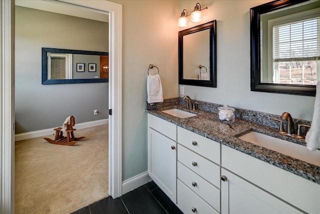 bathroom featuring double vanity, baseboards, and a sink