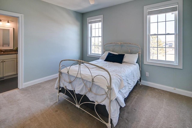 bedroom with light carpet, ensuite bath, and baseboards