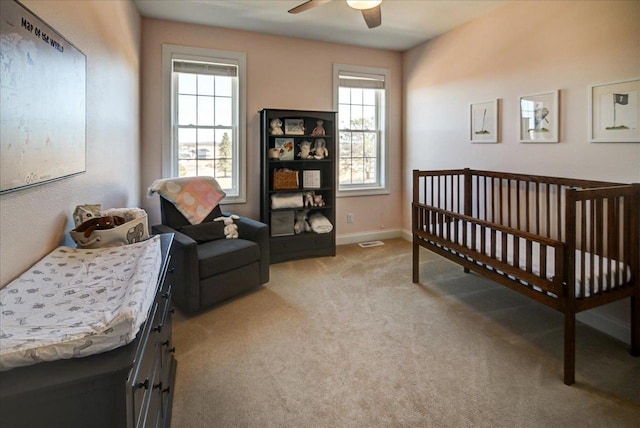 bedroom featuring light carpet, a ceiling fan, and baseboards