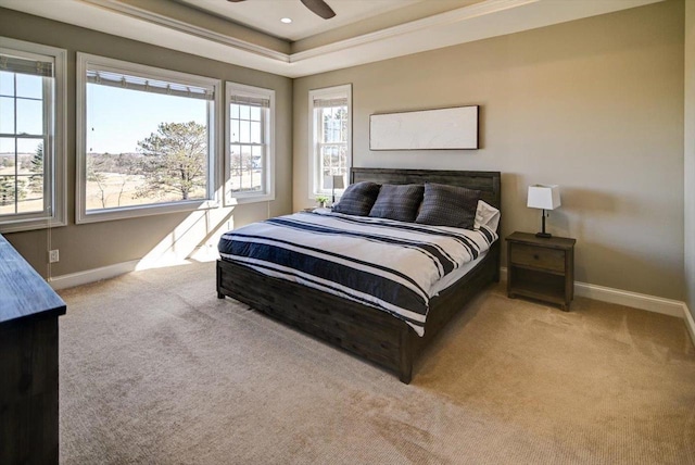 bedroom featuring light carpet, a raised ceiling, a ceiling fan, and baseboards