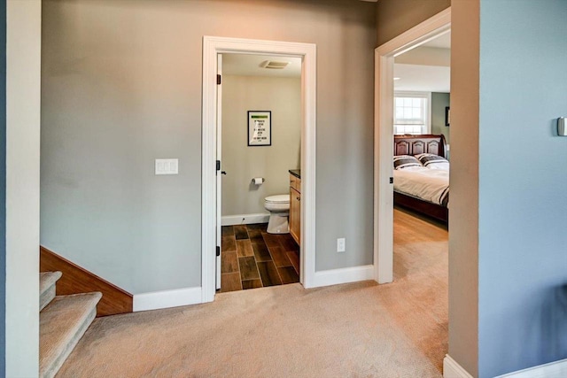 hall featuring carpet floors, visible vents, stairway, and baseboards