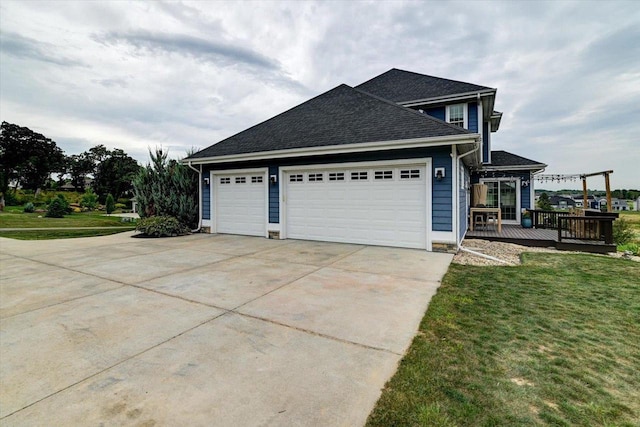 view of property exterior with roof with shingles, a lawn, an attached garage, driveway, and a wooden deck