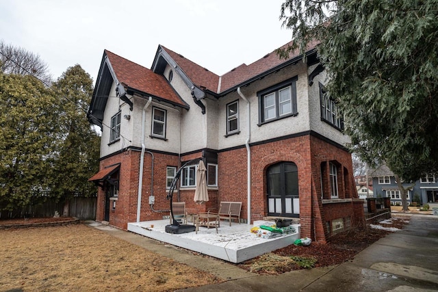 exterior space featuring stucco siding, a patio area, fence, and brick siding