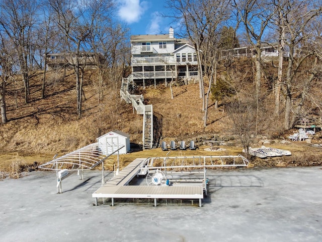 rear view of property with a storage shed, stairs, and an outdoor structure