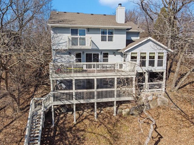 back of house with a balcony, a chimney, stairway, roof with shingles, and a wooden deck