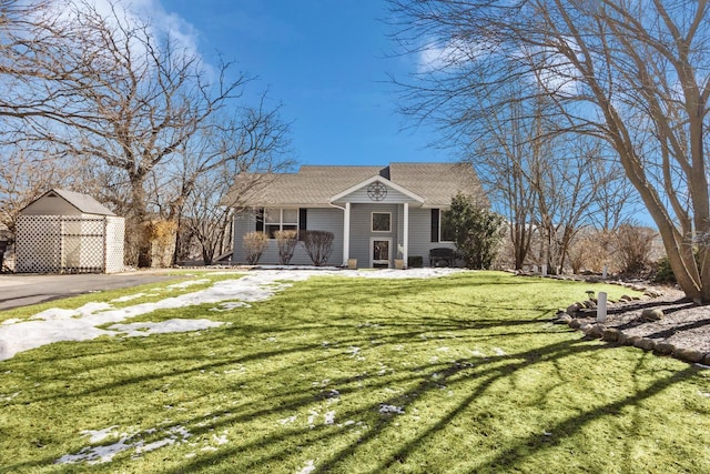 view of front of house featuring covered porch, a storage unit, a front yard, and an outbuilding