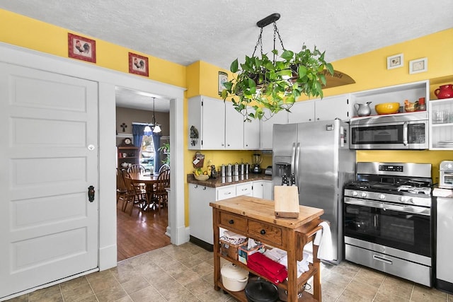 355 W Mill St, Columbus, WI 53925 - kitchen with appliances with stainless steel finishes, a textured ceiling, white cabinetry, and a chandelier