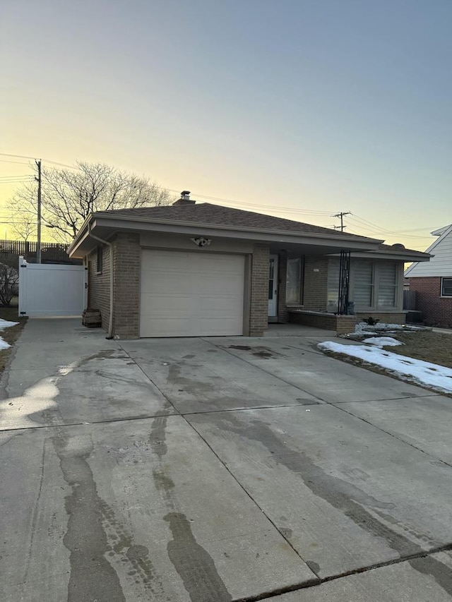 view of front facade featuring a garage, concrete driveway, brick siding, and fence