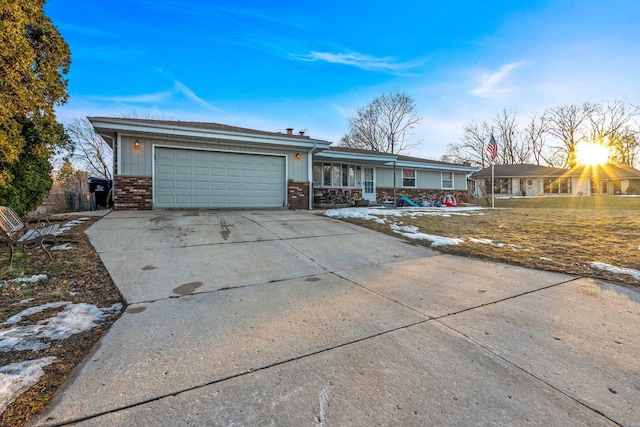 ranch-style home featuring a garage, concrete driveway, brick siding, and covered porch