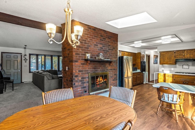 dining room with a textured ceiling, a skylight, a fireplace, visible vents, and dark wood-style floors