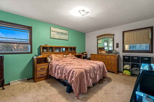 bedroom with baseboards, visible vents, and light colored carpet