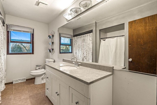 bathroom with toilet, vanity, visible vents, and baseboards