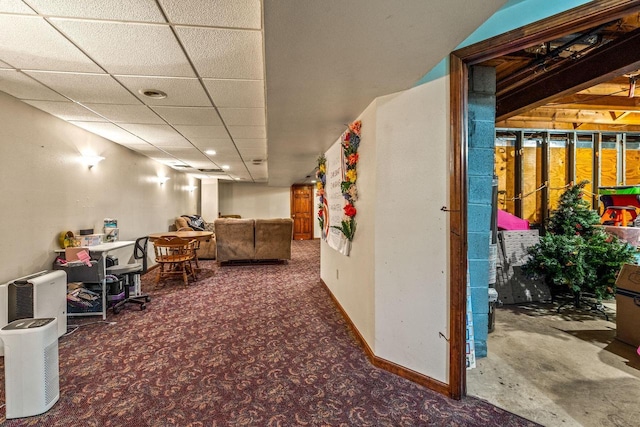 interior space featuring carpet floors, baseboards, and a drop ceiling