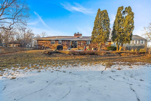 snow covered back of property featuring a chimney